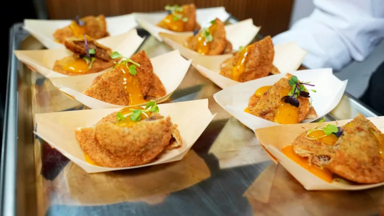 Salgados empanados servidos em papel no balcão de um ponto de venda de foodservice