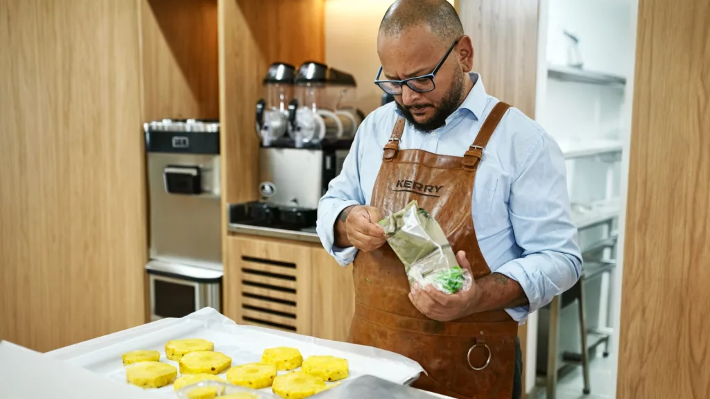 Chef de avental finalizando uma bandeja de tortinhas em cozinha profissional