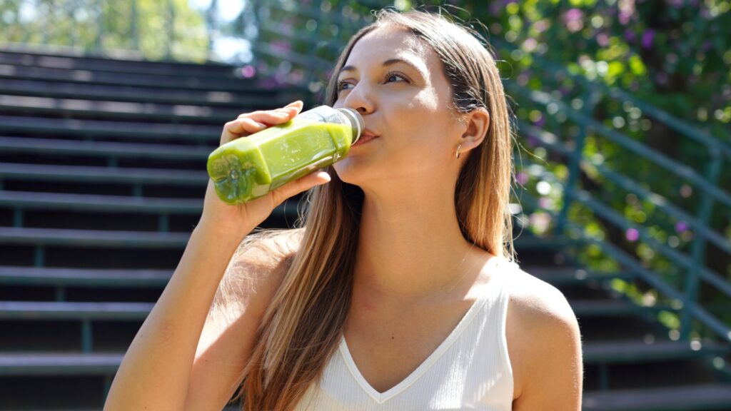 Consumidora bebiendo jugo verde funcional, ejemplo de la búsqueda de alimentos y bebidas más nutritivos