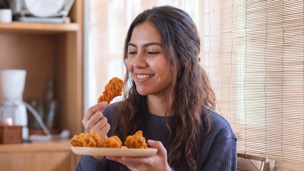 Consumidora saboreando frango empanado em casa, exemplo de qualidade preservada até o consumo